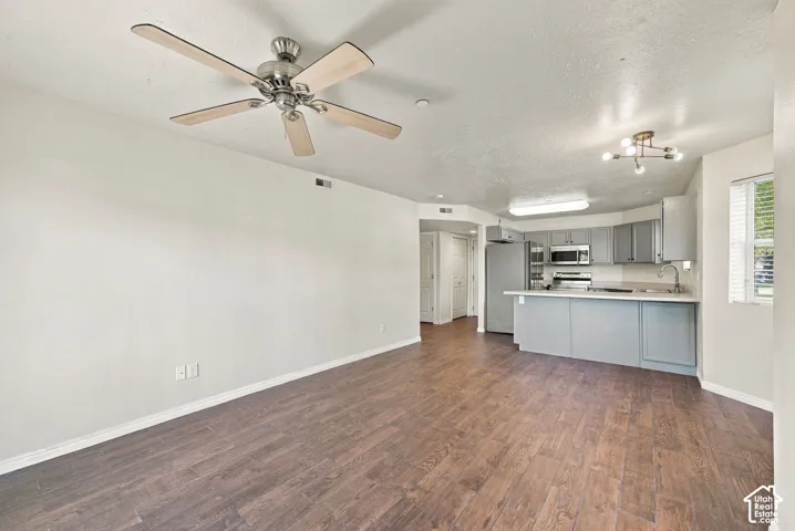 Open-concept interior featuring wood-finish flooring, a kitchen with grey cabinetry and a breakfast bar, and a ceiling fan