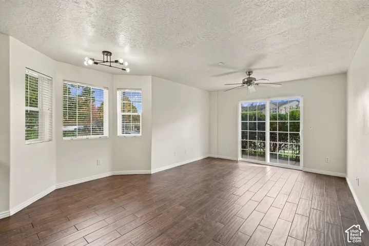 Spacious room featuring wood-finish flooring, a bay window configuration, a modern multi-arm light fixture, a ceiling fan, and glass-pane sliding doors