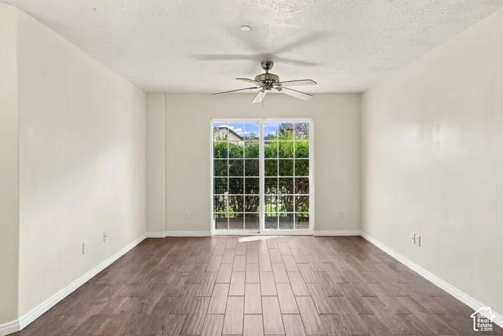 Interior space featuring wood-finish tile flooring, white walls, a ceiling fan, and white-framed sliding glass doors