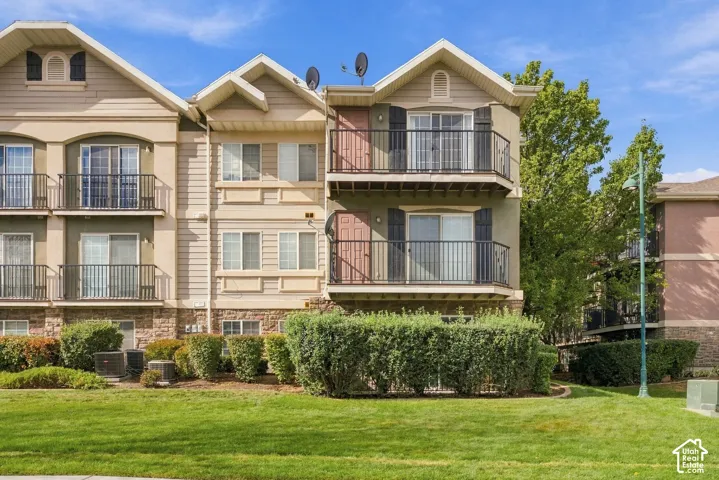 Multi-story residential exterior featuring stone veneer siding, dual-level iron-railed balconies, horizontal lap siding, and sliding glass entryways