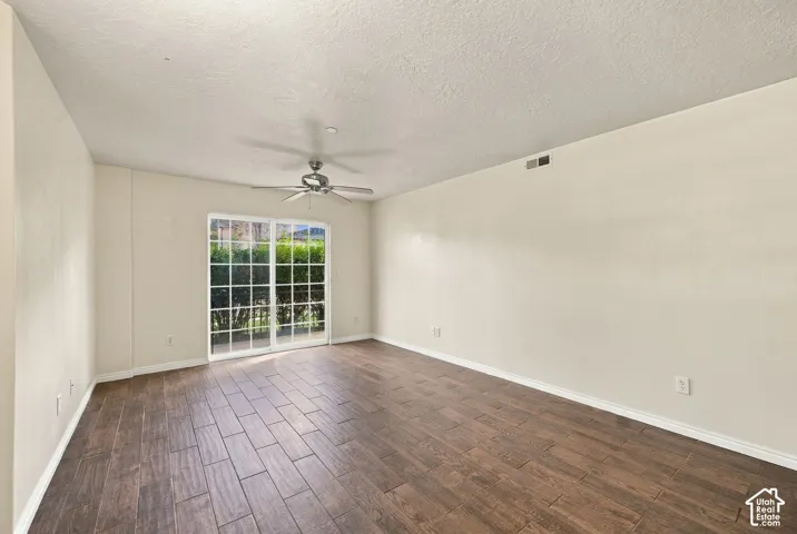 Room featuring wood-finish flooring, a metal ceiling fan, and sliding glass doors with grid detailing