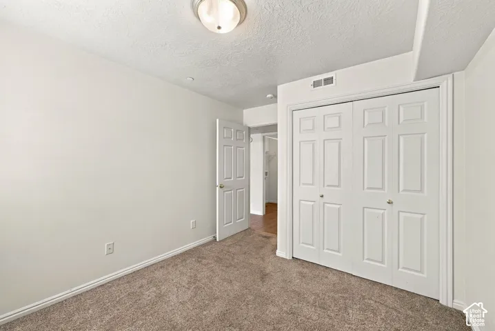 Spacious bedroom with neutral walls, neutral carpet flooring, and dual closets featuring six-panel white doors