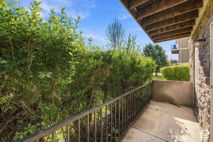 Covered balcony featuring concrete flooring, stone-veneer exterior wall, and metal railing