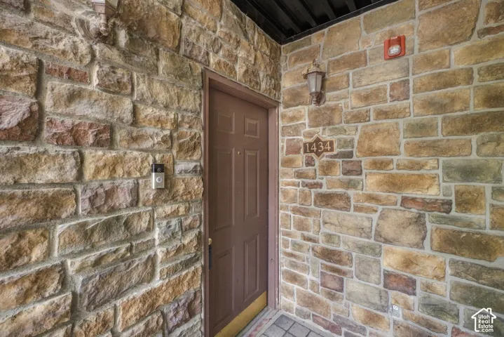 Textured stone exterior facade featuring a recessed entry door, wall-mounted coach lighting, and an integrated address plaque