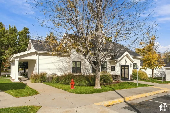 Exterior featuring light-toned horizontal siding, a covered carport with square columns, a steep-pitched roofline, and stone-veneer foundation detailing