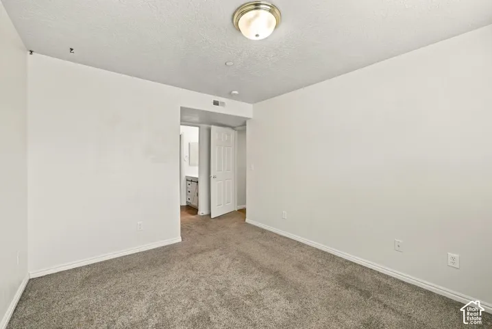 Neutral-toned carpeting, textured ceiling finish, and brushed nickel flush-mount overhead lighting, featuring a six-panel interior door