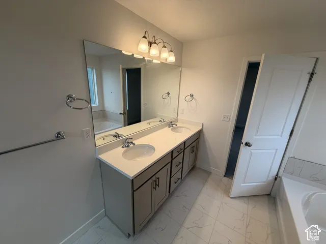 Double vanity featuring stone-composite countertop, dual drop-in sinks, polished chrome fixtures, and a large-format mirror with multi-bulb light fixture