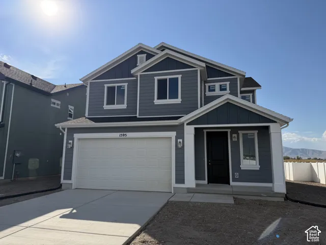 Two-story exterior featuring blue horizontal siding, vertical board-and-batten accents, white trim, a concrete driveway, and an attached two-car garage