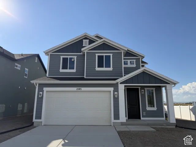 Two-story residence featuring blue horizontal lap siding, a two-car garage, white trim accents, a covered front entryway, and a concrete driveway