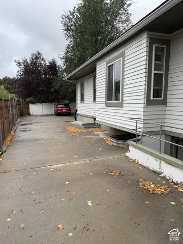 Exterior siding, concrete driveway, metal window wells, and exterior stair railing