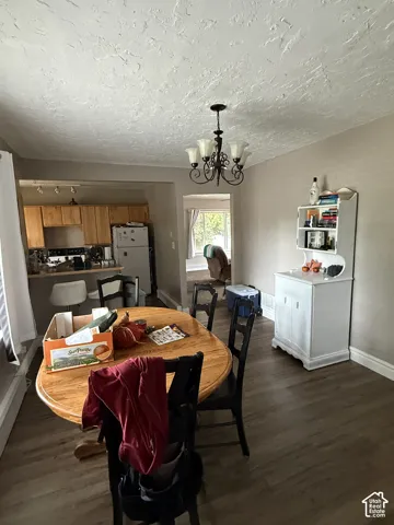 Dining area featuring wood-finish flooring, a decorative metal chandelier, and textured ceiling finish