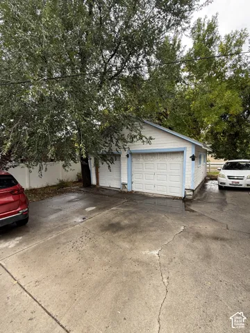 Detached two-car garage featuring horizontal siding, asphalt shingle roofing, and exterior lighting fixtures, set on a concrete driveway