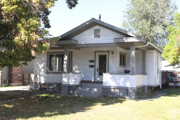 Single-story residence featuring a covered front porch with tapered columns, white lap siding, and a gabled roofline
