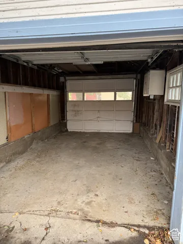 Detached garage structure featuring a concrete floor, windowed overhead garage door, and exposed stud-wall construction