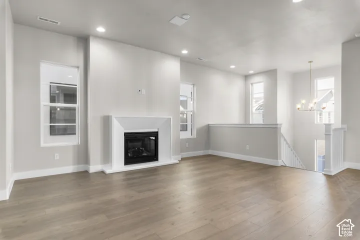 Open interior featuring wood-finish flooring, a contemporary fireplace with a geometric surround, recessed lighting, and a multi-tiered chandelier