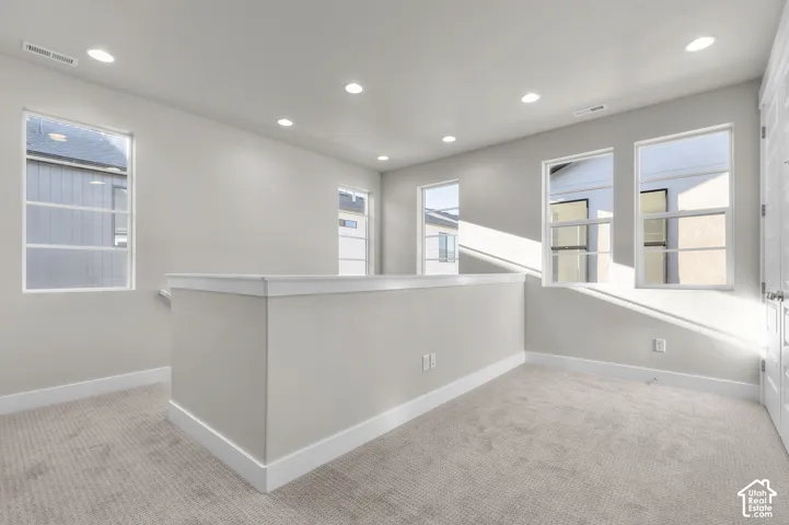 Open space featuring recessed lighting, wall-to-wall carpeting, and multiple windows with white frames