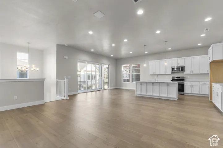 Open-concept interior featuring wood-finish flooring, white cabinetry, a center island, recessed lighting, and multi-panel sliding glass doors