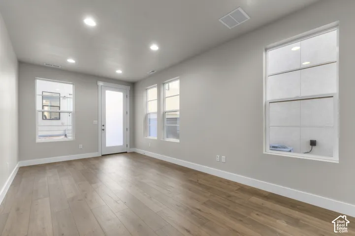 Neutral-toned interior featuring wood-finish flooring, recessed lighting, and multiple windows