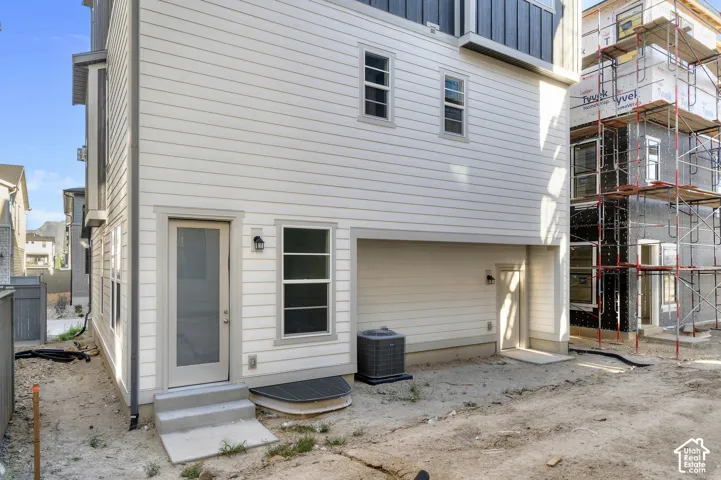 Multi-story exterior featuring horizontal siding, vertical accent panels, multiple fixed and single-hung windows, exterior wall-mounted light fixtures, and a recessed service entrance