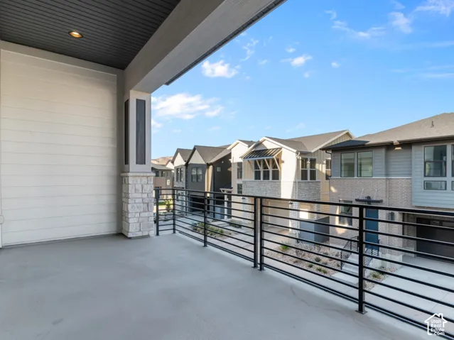 Covered balcony featuring horizontal metal railings, stone-base pillar, recessed ceiling lighting, and horizontal lap siding