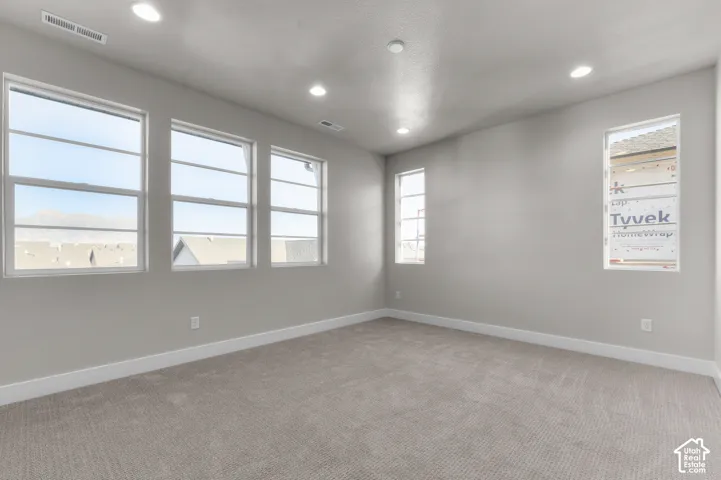 Interior space featuring neutral-toned carpeting, recessed ceiling lighting, and multiple large windows