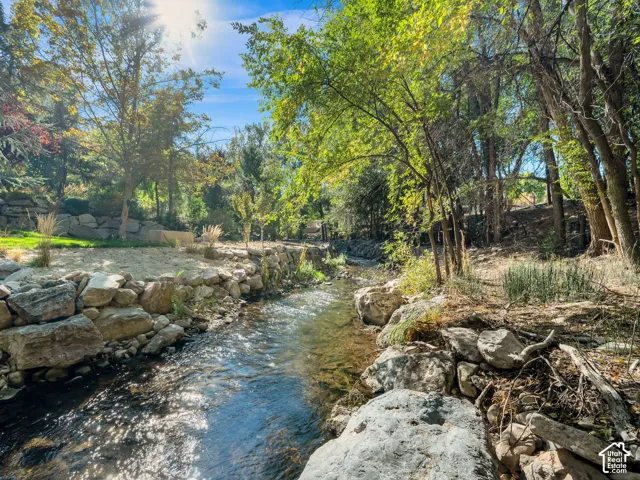 Natural water feature, stone retaining walls, mature trees, and landscaped grounds