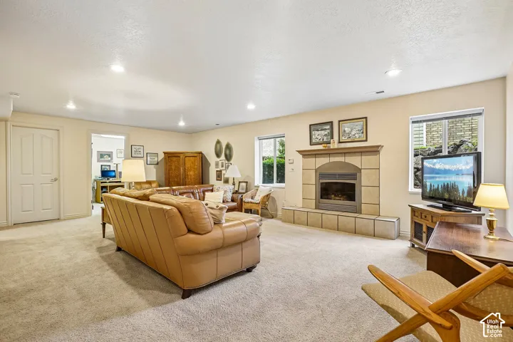 Living space featuring a fireplace with a tiled hearth and surround, recessed lighting, and dual windows