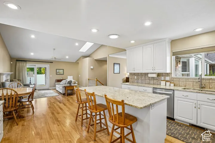 Kitchen featuring a central island with stone-finish countertops, white cabinetry, recessed lighting, and wood-finish flooring extending into the surrounding area