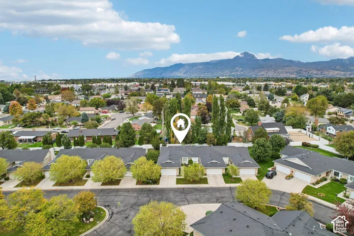 Aerial perspective of a single-story residential structure featuring a multi-car garage, asphalt shingle roofing, and mountain backdrop