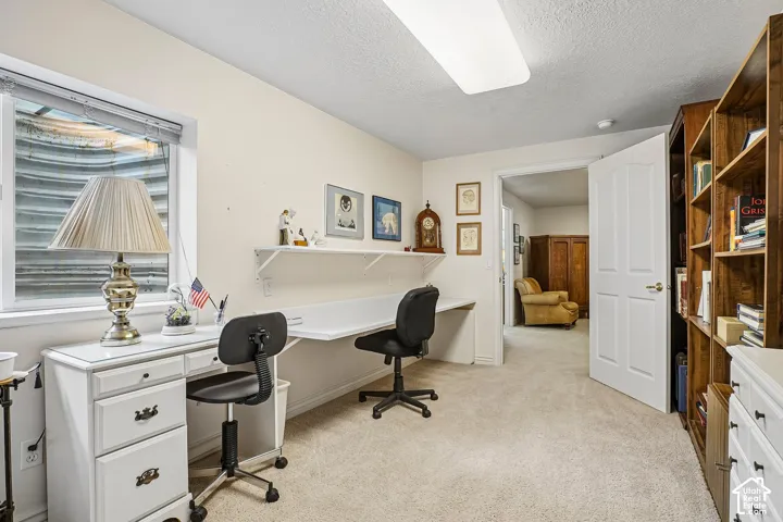 Built-in wall shelving, integrated wall-mounted desk, neutral carpeting, and window with an egress well