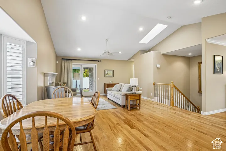 Vaulted ceilings with recessed lighting, skylight, wood-finish flooring, fireplace, and staircase with wooden banister