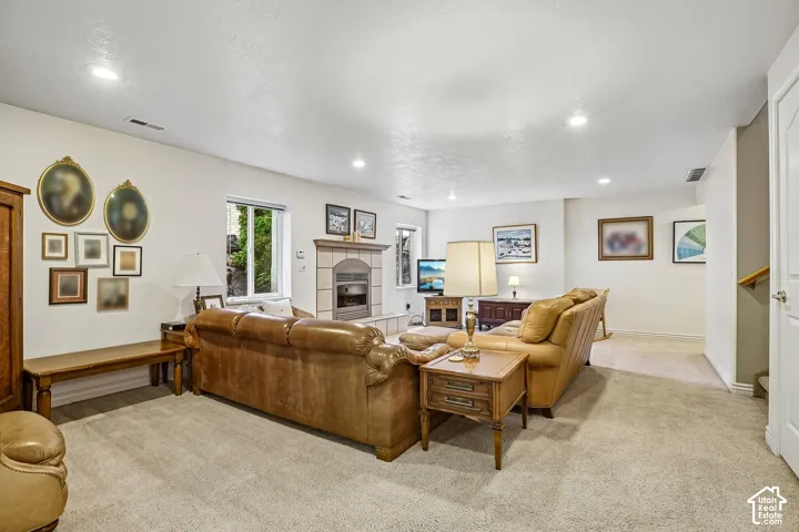 Spacious living area featuring neutral carpeting, recessed lighting, and a stone-surround fireplace