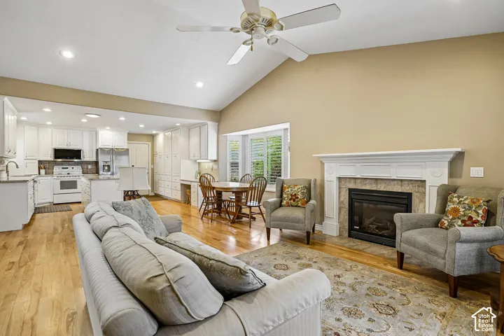 Vaulted ceilings, wood-finish flooring, recessed lighting, and a fireplace with a detailed mantel