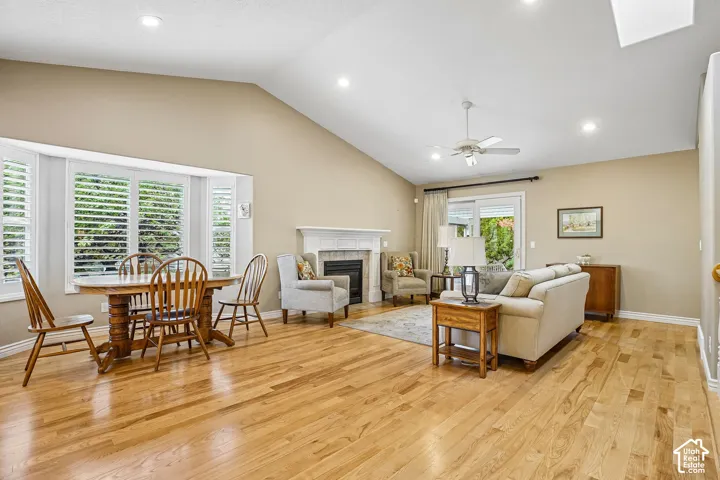Vaulted ceilings, wood-finish flooring, recessed lighting, white-trimmed fireplace with hearth, and bay window featuring plantation shutters