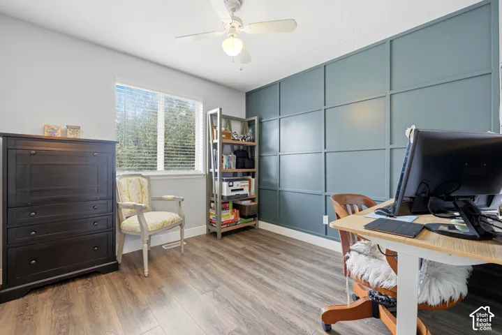 Room featuring an accent wall with board-and-batten molding, wood-finish flooring, and a ceiling-mounted light fixture with a fan