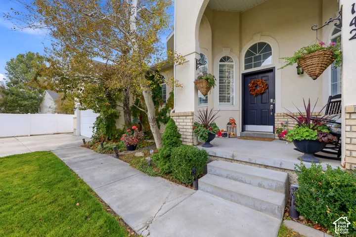 Covered front porch featuring an arched entryway, masonry exterior accents, concrete steps, and a multi-pane arched transom window above the front door
