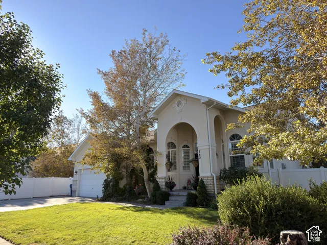 Stucco exterior featuring an arched entryway, stone-veneer accents, arched windows, and an attached two-car garage