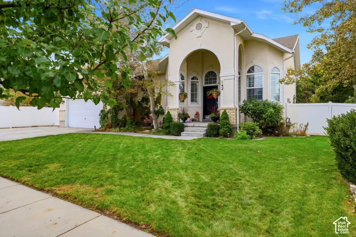 Stucco exterior featuring an arched entryway, stone accent detailing, segmented windows, and an attached multi-car garage