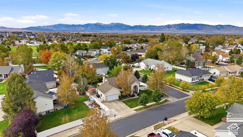Aerial perspective featuring residential lots, paved streets, mature trees, and a mountain range backdrop