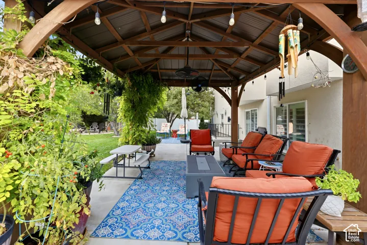 Covered wood-frame gazebo with a metal roof and built-in ceiling fans, set upon a concrete patio
