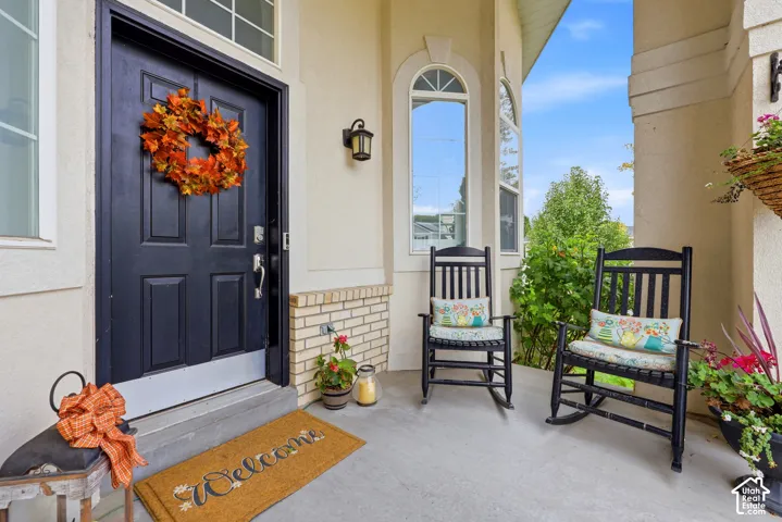 Covered entryway featuring a solid-panel door, masonry skirting detail, arched windows, and wall-mounted exterior lighting