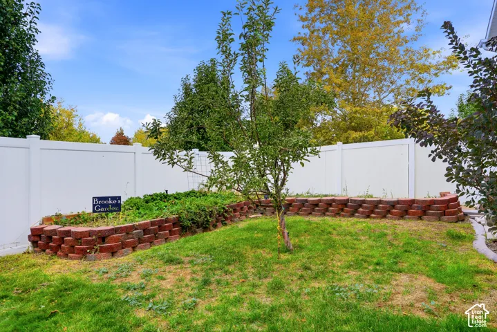 Backyard featuring a raised brick garden bed, privacy fencing, and a mature tree