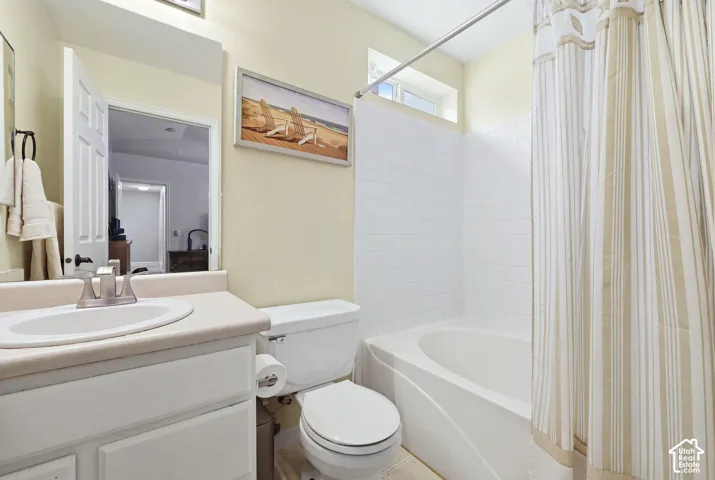 Bathroom in primary bedroom featuring a white vanity with an integrated oval sink, matte finish countertop, white square wall tile surrounding the bathtub, and a rectangular transom window