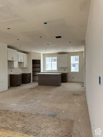 Kitchen featuring two-tone cabinetry, central island with countertop, built-in pantry shelving, and dual windows