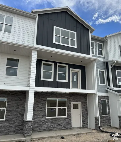 Multi-level exterior featuring a combination of stone veneer and vertical panel siding, recessed lighting, and a concrete patio