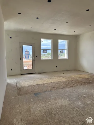 Unfinished interior featuring recessed lighting, dual vertical windows, and exterior entry door