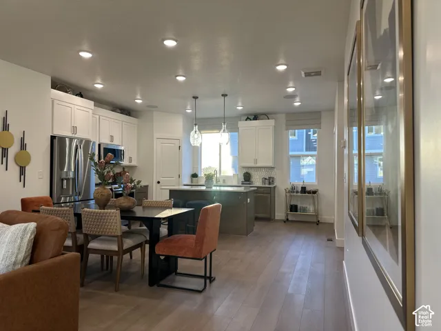 Kitchen featuring wood-finish flooring, white cabinetry, a center island with stone countertop, stainless steel refrigerator, and recessed lighting