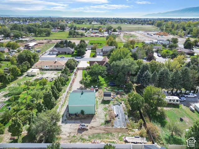 Expansive lot featuring a detached workshop with a metal roof, mature evergreen trees, and perimeter fencing