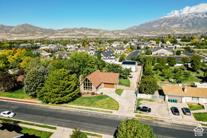 A-frame residence with expansive glass glazing, attached garage, detached workshop with solar panel array, and mature tree-lined landscaping situated against a mountain backdrop