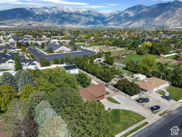 Aerial perspective featuring mountain backdrops, mature trees, concrete driveways, and brown shingle roofing